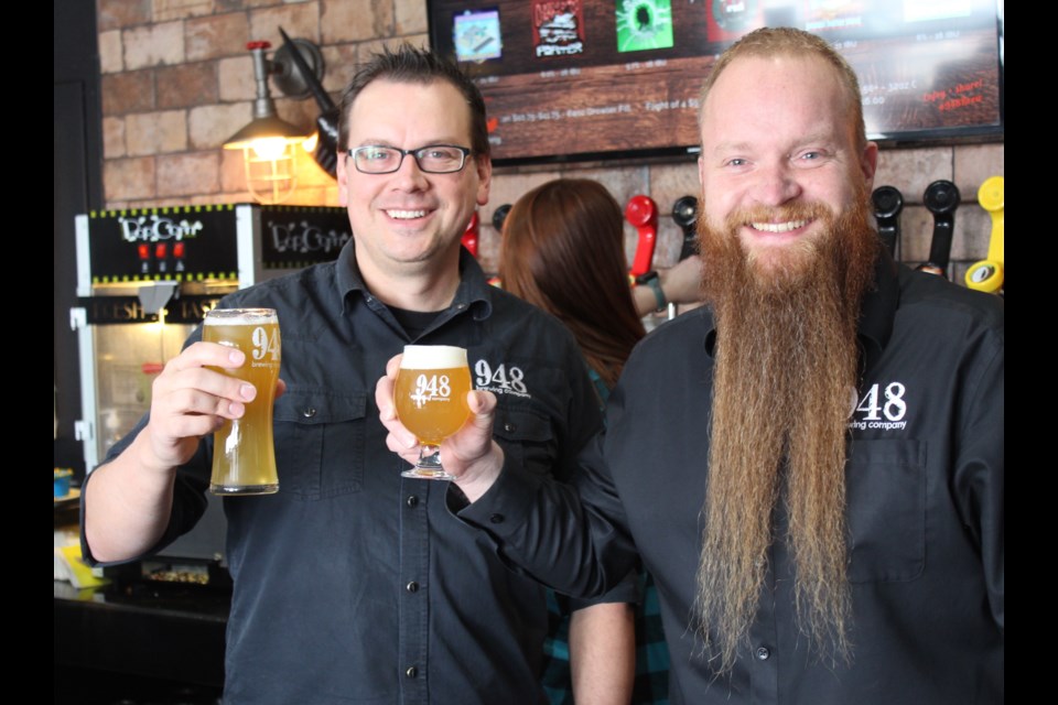 948 Brewing Company co-owners Kyle Wudrich (left) and David Schroter hoist a glass to celebrate their official grand opening after three-years delay due to COVID-19 on March 18.