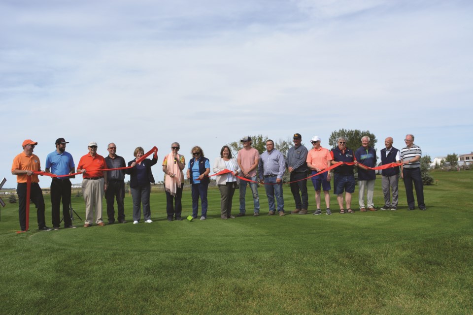 Representatives from the Town of Crossfield, Optimist International, the Crossfield Chamber of Commerce, and Collicut Siding Golf Club, gather together on Aug. 30 to cut the ribbon officially declaring Lil' Optimist Loop open. 