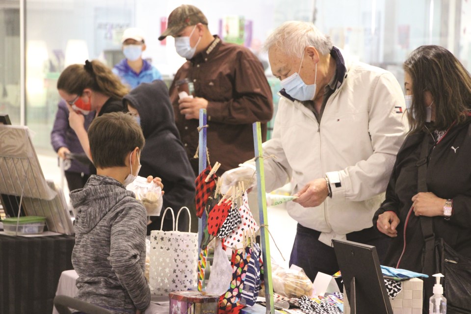 Some interested buyers peruse a selection of crafts at a boy's booth at the New Horizon Mall Kid's Craft Fair on June 19. 