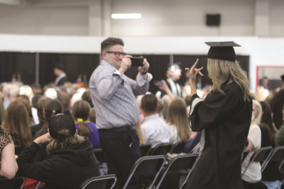 A George McDougall High School graduate poses for a photograph as she makes her way to her seat at the 2022 convocation ceremony at Genesis Place on May 26.