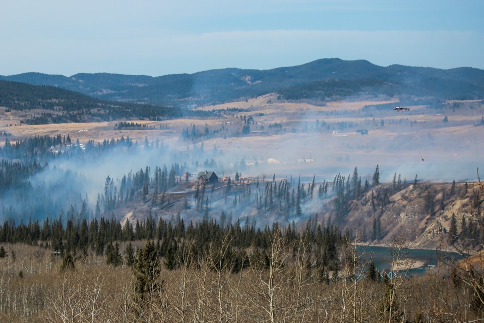 An Alpine Helicopter aerially assists firefighters on the ground as a wildfire burns near a residence off of Highway 1A, about one kilometre west of the The Wildcat Hills Gas Plant on April 1.
