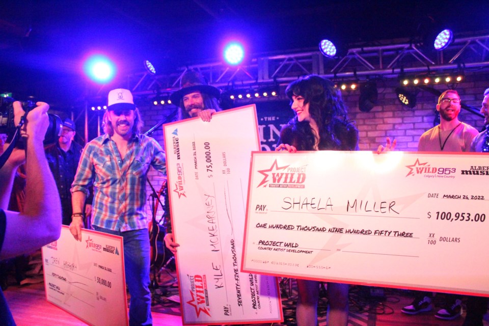 (Left to right) Drew Gregory, Kyle McKearney and Shaela Miller pose with their winning cheques on March 26.
