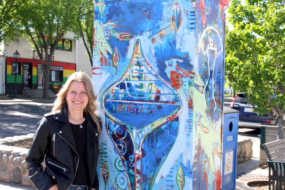 Airdrie artist Veronica Funk stands next to her recently rejuvenated utility box mural, Honouring the Ancestors.