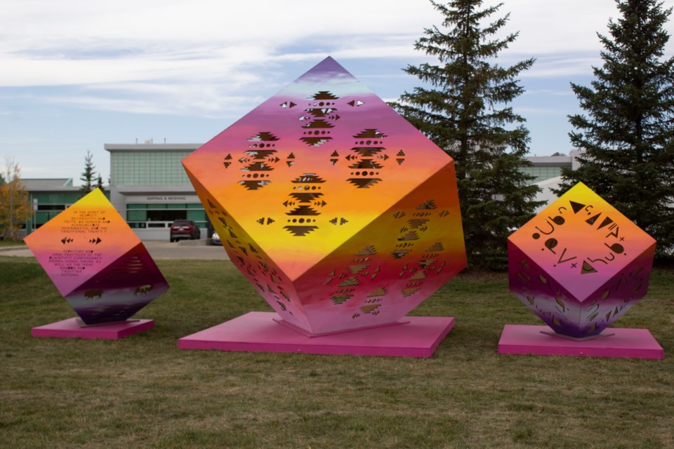 The exhibit consists of three colourful cubes bearing Indigenous land acknowledgments.