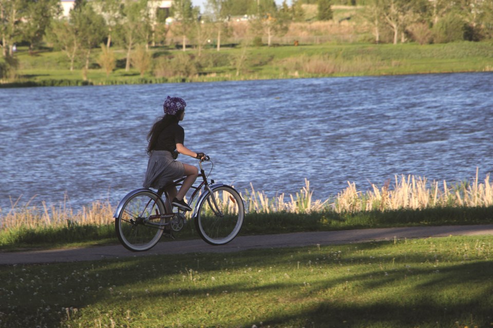 A cyclist rides past the waters of East Lake in Airdrie on a recent Friday evening. 