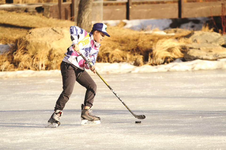 A young hockey player works on his stick-handling at Nose Creek Pond on an unseasonably warm December afternoon. Photo by Scott Strasser/Airdrie City View.