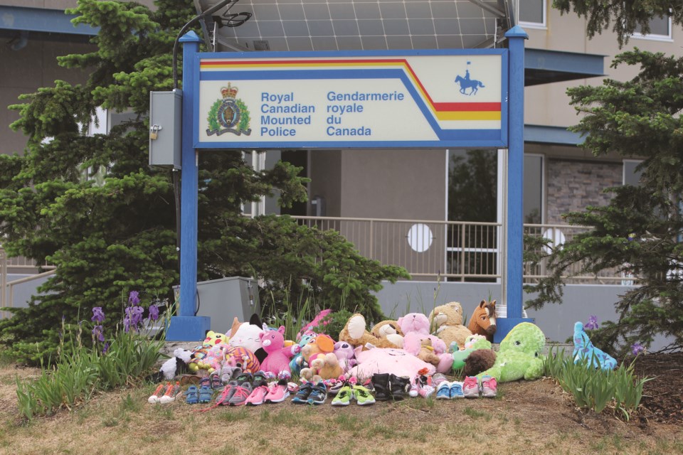 Children's shoes and stuffed animals are placed in front of the Royal Canadian Mounted Police Airdrie detachment on June 19 in memory of children who died in the residential school system. 