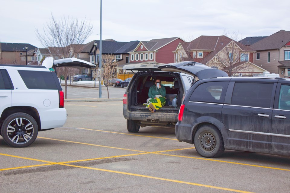 Three friends enjoy some socialization at Chinook Winds Regional Park, parking their vehicles a safe distance away from one another and chatting from their trunks. Photo: Ben Sherick/Airdrie City View
