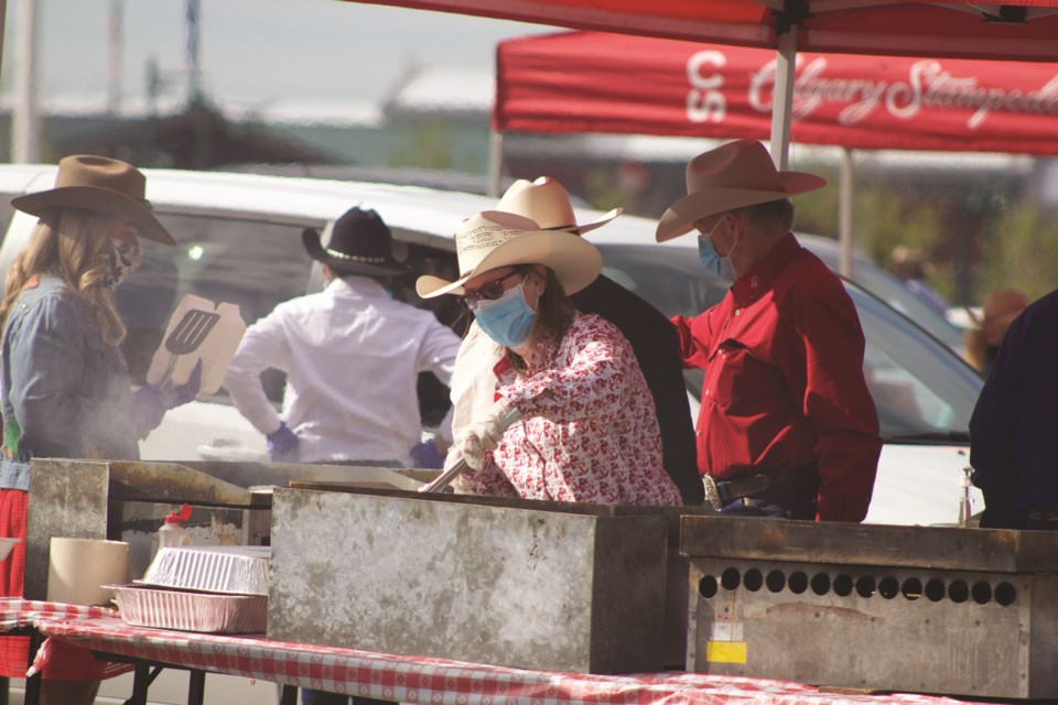 Although the Calgary Stampede is cancelled this summer due to COVID-19, masked volunteers still worked the grills during a drive-thru pancake breakfast at CrossIron Mills mall July 4.
Photo by Ben Sherick/Airdrie City View