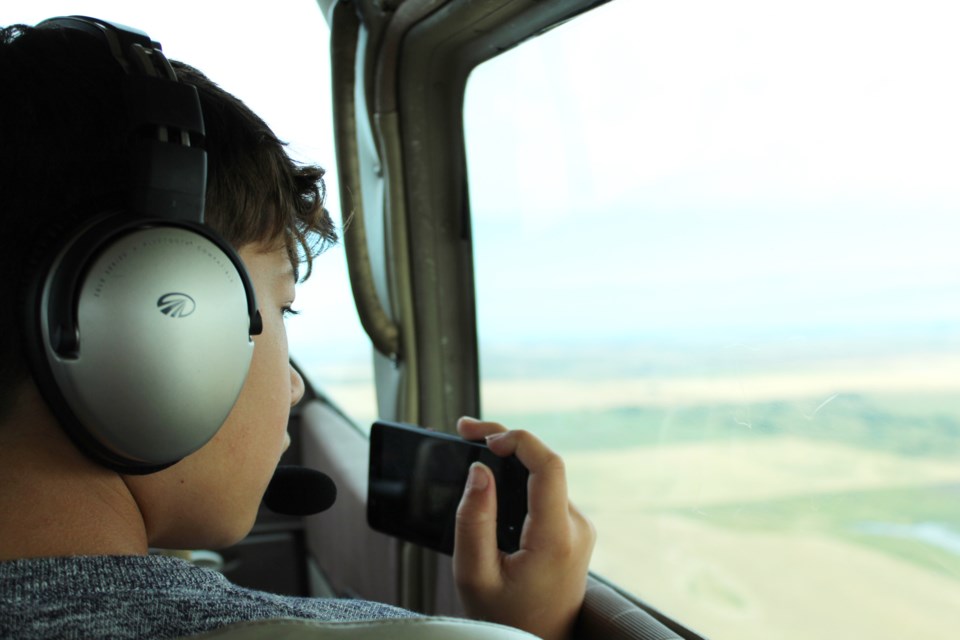 Twelve-year-old Jacob Rogers, a student at Windsong Heights School in Airdrie, takes photos from the co-pilot seat of a search-and-rescue plane Sept. 14, during the COPA For Kids event. 
Photo by Scott Strasser/Rocky View Publishing