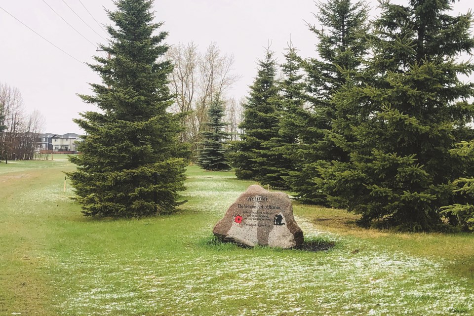 A memorial stone is seen amidst green grass and trees at Veteran's Peace Park in Crossfield on a recent Saturday afternoon. 