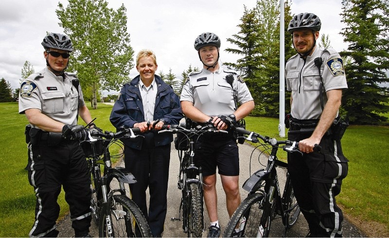 Peace officer Cale Feduniw, Airdrie RCMP Cst. Patti Reid, Cst. Rob Frizzell, and Peace officer Scott Donselaar pose for photos with their bikes in Nose Creek Park, June 15.