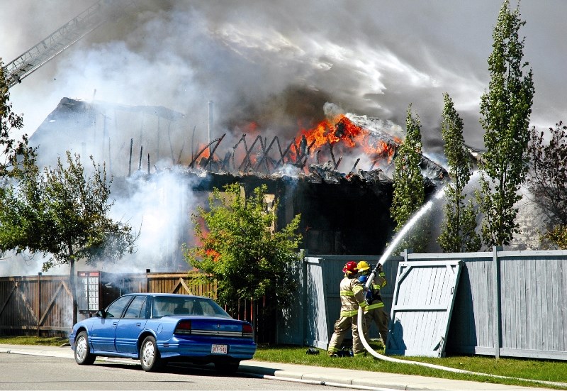 Firefighters battle a blaze on July 29 in the community of Sunridge. The fire began after a thermal reaction caused a bucket full of linseed-oil-soaked rags to ignite. Damage 