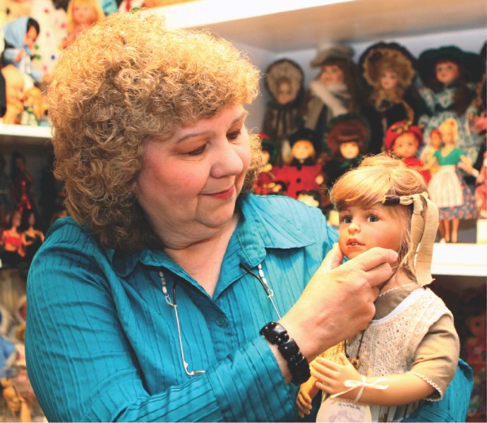 Edda Doell poses with just some of her collection of various dolls and toys at her home in Airdrie Aug. 5.
