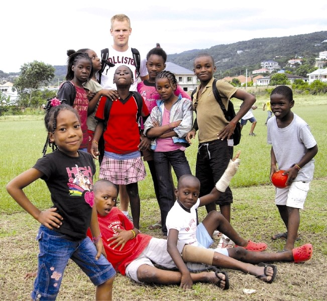 Jared Lange poses with local children during his visit to Jamaica last month, where he delivered six bags of Airdrie soccer jerseys.
