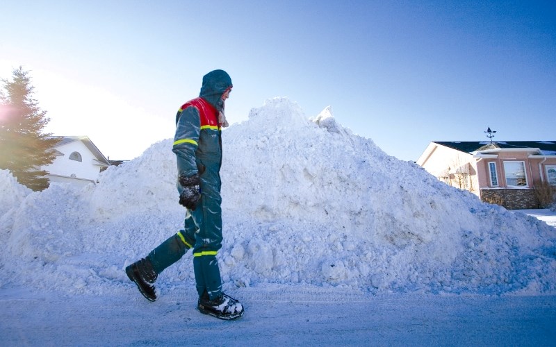 Airdrie resident Rob Bull walks past just one of three huge snow piles on Woodside Cres., Jan. 11. City crews have been working overtime to keep the roads in drivable shape.