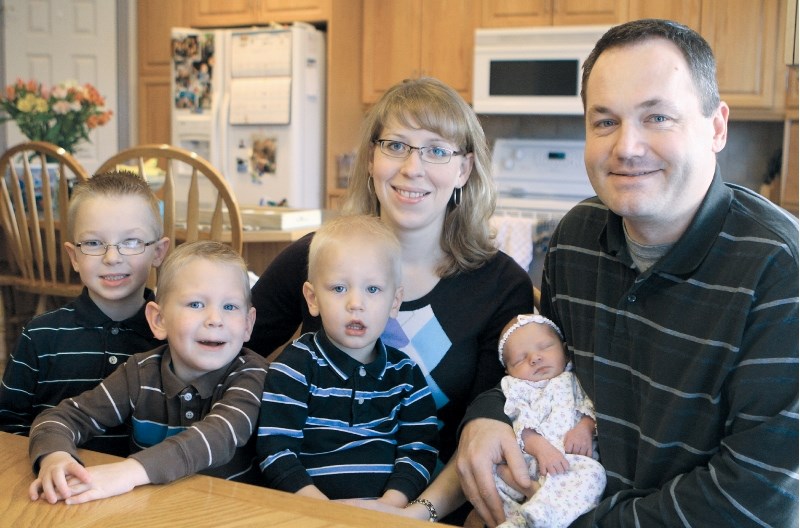 Six-year-old Nathaniel, four-year-old Reuben, two-year-old Jesse, and parents Kim and Daniel pose for a photo with the newest addition to their family, six-day-old Madeline