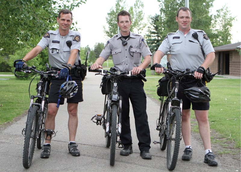 Const. Dave Henry, Municipal Enforcement officer Cale Fedrau and Const. Rob Frizzell pose for photos with their bikes in Nose Creek Park July 19.
