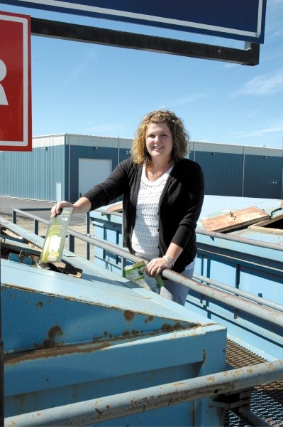 Jen Munro recycles a magazine at the Airdrie Recycling Depot, Aug. 23. Airdrie residents will continue to bring their recycling to one of the two City depots as there are no