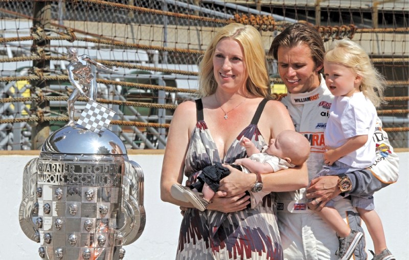 2011 Indianapolis 500 winner Dan Wheldon, holding his eldest son Sebastien, glances at his youngest son Oliver who is being held by his wife Susie during the Indy 500 winners 