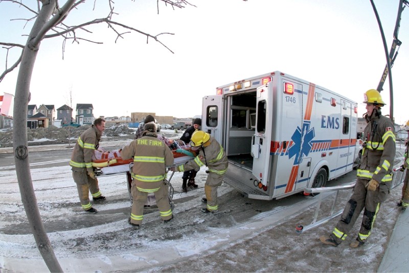 Four Airdrie firefighters load a man, who was injured on a construction site in Williamstown when he fell into the basement of a house, into an ambulance, Jan. 10. Airdrie