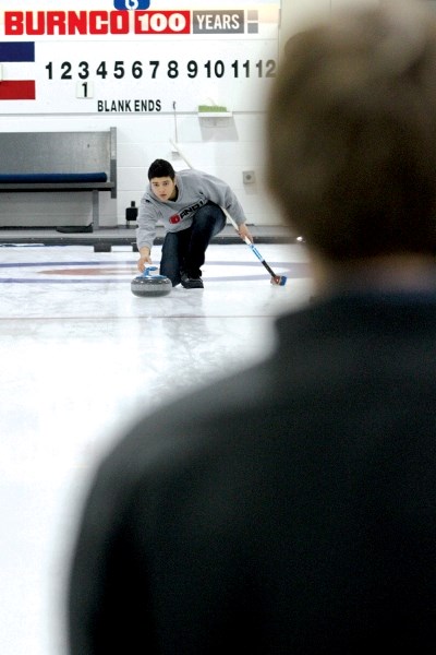George McDougall sophomore Moheeb Baroud sends a rock down the ice during the Rocky View Schools&#8217; curling divisionals, held at the Airdrie Curling Club Feb. 8 and 9.