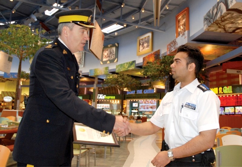 Insp. Tony Hamori, officer in charge of Airdrie RCMP Detachment, presents Khalid Shahid, a CrossIron Mills mall security officer with a Detachment Commander&#8217;s