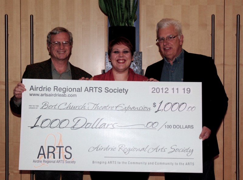 Stewart McLeish of the Airdrie Regional Arts Society (ARTS) and Ken Vickets ARTS president, present Kim Cheel of the Bert Church Theatre Enhancement Initiative with $1,000.