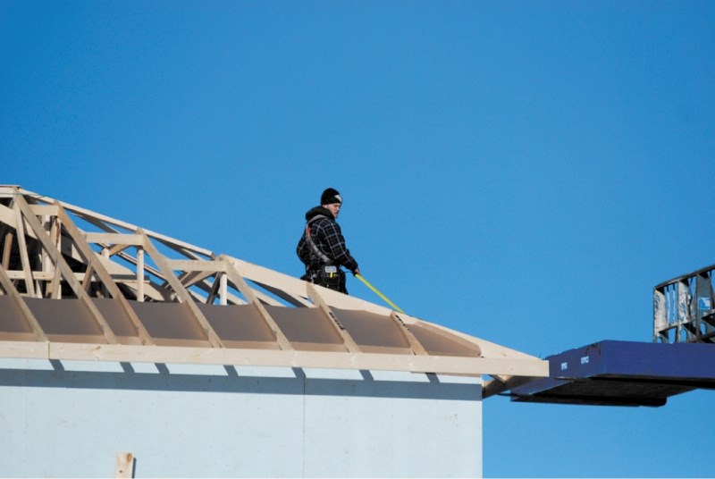 A construction worker labours on the roof of a new home in Airdrie, Jan. 24. Home sale growth in Airdrie and Cochrane outpaced Calgary&#8217;s in 2012.