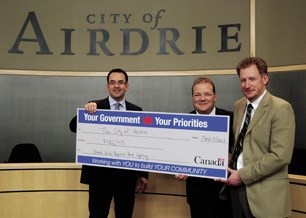Wild Rose MP Blake Richards presents Mayor Peter Brown and Lorne Stevens, Airdrie&#8217;s director of community infrastructure witih a cheque for more than $100,000. The