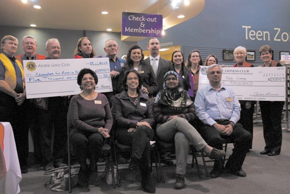 Members of the Airdrie Lions Club, the Rotary Club of Airdrie and Airdrie Lioness Club present the Advocates for Airdrie Public Library with donations totally $12,600, Nov.