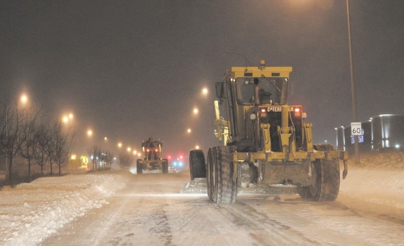 A pair of road graders work to clear Yankee Valley Boulevard in the evening on Dec. 2. Graders, plows and sand and salt trucks were out in force throughout the course of the