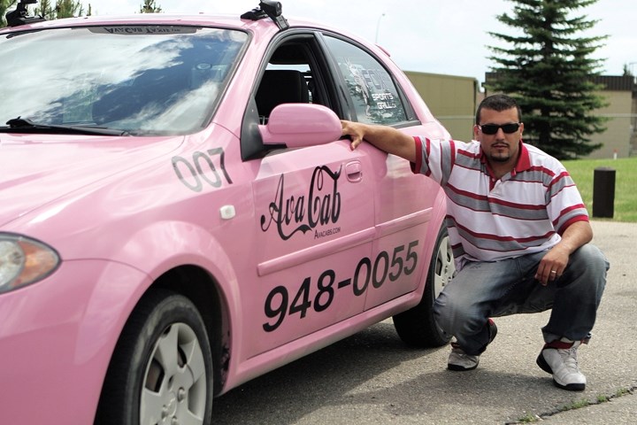 Mohammed Benini crauches beside one of his pink Avacabs.