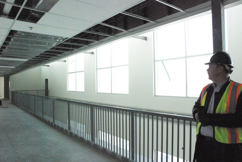 Ron Smith, director of advancement for Airdrie Koinonia Christian School, looks at the second floor atrium walkway located in the school&#8217;s new building March 5. Smith