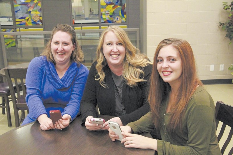 Three of the administrators of the Airdrie Moms Facebook page, (from left) Tanya Cole, Mandi Carter and Tayona Wheler, keep track of postings to the page via their cell