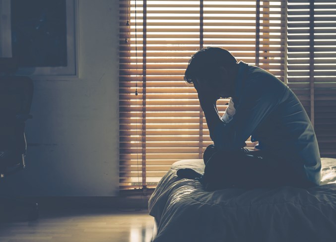 Sad businessman sitting head in hands on the bed in the dark bedroom with low light environment, dramatic concept, vintage tone color