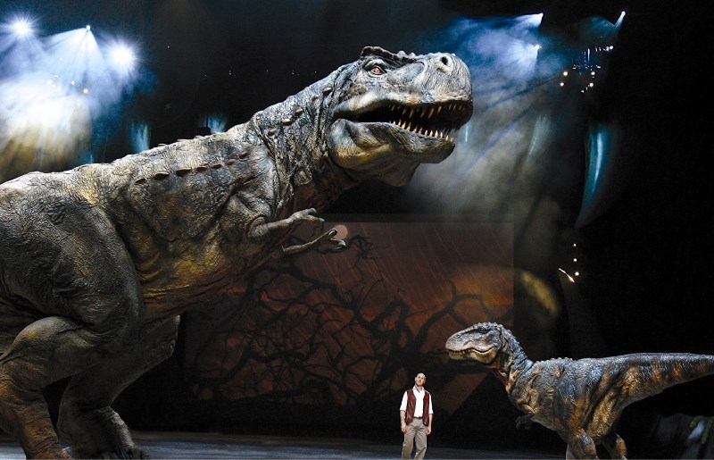 An adult Tyrannosaurus Rex and offspring with the narrator Huxley in a scene from Walking With Dinosaurs &#8211; The Arena Spectacular.