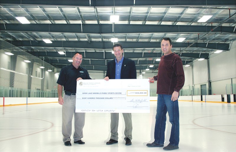 Robin Mitchell (left) and John Clarkson (right) of the Spray Lake Sawmills Family Sports Centre board of directors receive a $800,000 cheque from Rocky View County&#8217;s