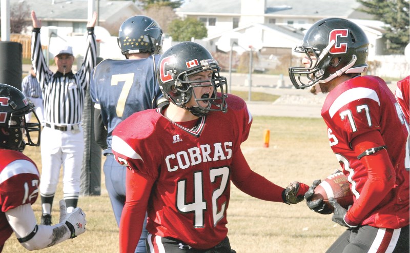 Cochrane Cobras&#8217; defenders, celebrate linebacker Lochlan Walker&#8217;s (No. 77) first quarter touchdown during the team&#8217;s 54-7 win over the Bow Valley Bobcats.
