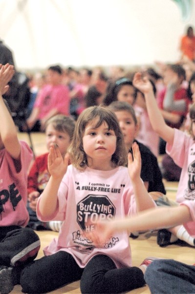 Grade 1 student Emily Trebinkski of Langdon School claps her hands during a singing of We Are the World, March 4. The school sold T-shirts in support of Pink Shirt Day, a