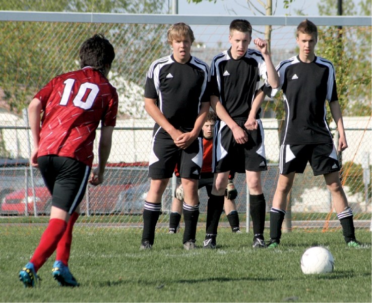 Mustangs netminder Connor Willmore peers through his defenders as a Chetermere Lakers lines up a free kick, May 31. The Mustangs won 3-2 to advance to the divisional