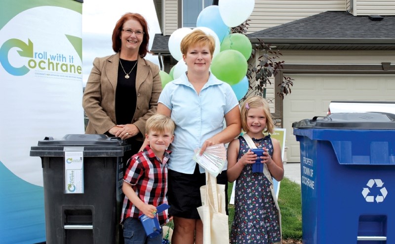 Deputy Mayor Joanne Churchill presents Cochranites Jennifer, Sofia and Connor Preece with the first curbside carts ahead of the Town&#8217;s new automated waste and recycling 
