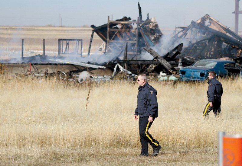 Police officers comb the scene of a fire on an acreage near Chestermere, Oct. 14. A home was destroyed and one child was presumed dead as of press time.