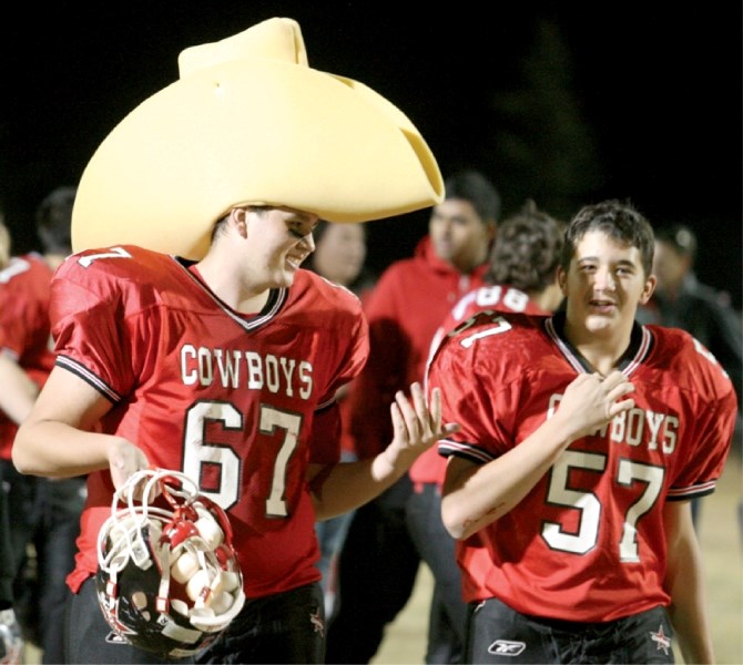 Cowboys&#8217; linemen Adam Davis, in the oversized novelty cowboy hat, and Dakota Duncan celebrate Chestermere&#8217;s 36-15 victory over the Bert Church Chargers, Oct. 14.
