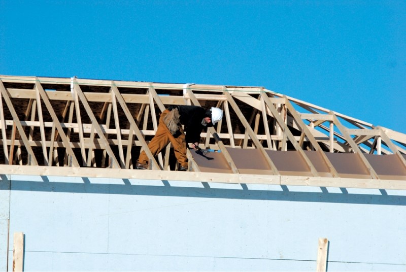 A construction worker labours on the roof of a new home in Airdrie, Jan. 24. Home sale growth in Airdrie and Cochrane outpace Calgary&#8217;s in 2012.