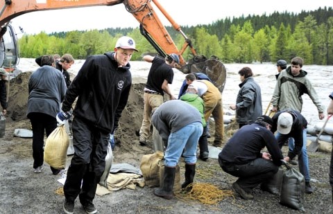 Redwood Meadows residents frantically sandbag at a portion of the berm threatened by the Elbow River on June 20.