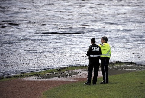 Cochrane Peace officers look over the rising Bow River on June 20.