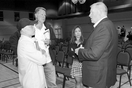 Air Bouphasiry, Bragg Creek resident and business owner, (far left), his landlord Dick Koetsier (left), and his wife Nok (right), speak with Kyle Fawcett, associate minister