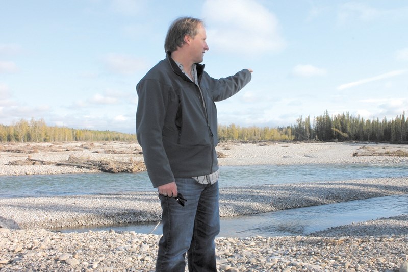 Redwood Meadows Mayor John Welsh stands on his community&#8217;s berm to survey the new path of the Elbow River. The berm prevented the townsite from flooding in June, but