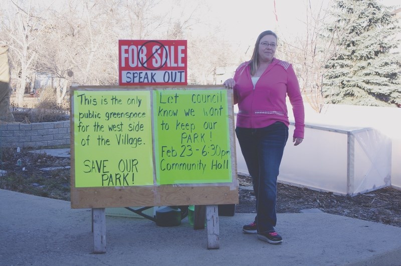 Acme resident Leona DeKoter stands with the sign she posted advertising a public meeting to potentially rezone the Prospect Avenue park for future residential development.